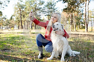 Pretty blonde girl walking with dog in the forest. Animal concept.