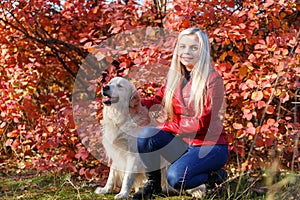 Pretty blonde girl walking with dog in the forest. Animal concept.