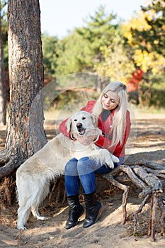 Pretty blonde girl walking with dog in the forest. Animal concept.