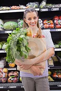 Pretty blonde holding bag with bread and vegetable