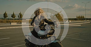 Pretty blonde lady woman dressed in black leather jacket sitting on motorbike