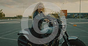 Pretty blonde lady woman dressed in black leather jacket sitting on motorbike