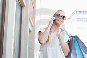 Pretty blonde making a call holding shopping bags