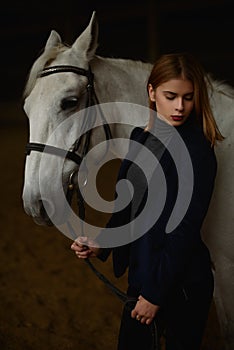 Pretty blonde poses with white horse.