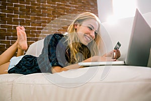 Pretty blonde relaxing on the couch using laptop