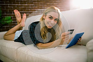 Pretty blonde relaxing on the couch using tablet