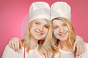 Pretty blonde twins posing for double portrait as bakers