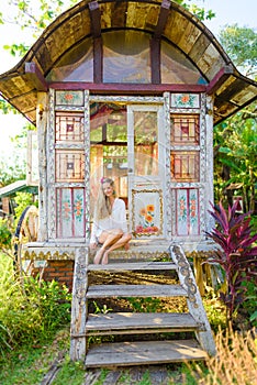 Pretty blonde woman and antique gypsy caravan