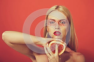 Pretty blonde woman with creative fashionable makeup hold grapefruit, vitamin