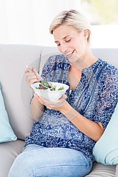 Pretty blonde woman eating bowl of salad