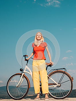Pretty blonde woman enjoy her walk with bike. Cycling concept. Beautiful woman took a break while riding her vintage