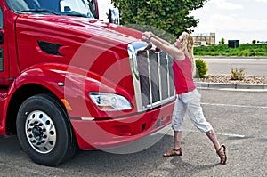 Pretty blonde woman opening a truck hood.