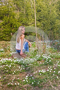 Pretty blonde woman on a spring meadow in blossom flowers