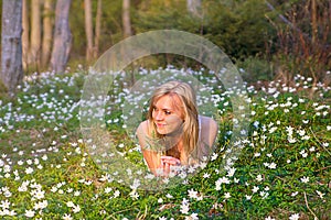 Pretty blonde woman on a spring meadow in blossom flowers