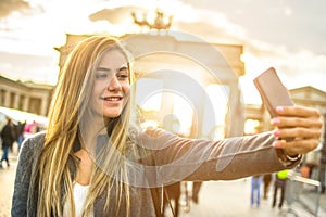 Pretty blonde woman taking a selfie in front of the Brandenburg Gate in Berlin, Germany