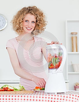 Pretty blonde woman using a mixer in the kitchen