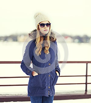 Pretty blonde woman wearing a jacket, hat and sunglasses