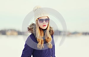 Pretty blonde woman wearing a jacket, hat and sunglasses