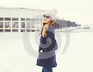 Pretty blonde woman wearing a jacket, hat and sunglasses in winter