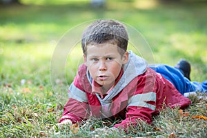 Pretty boy laying in grass at autumn season