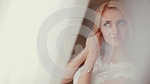 Pretty bride looking out of window and smiling on her wedding day