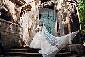 Pretty bride looks over her shoulder while wind blows her veil