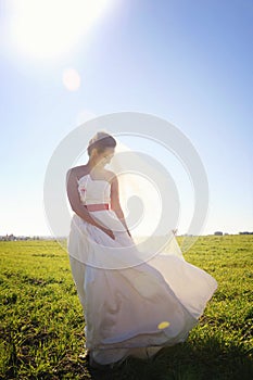 Pretty bride walking on field with kite