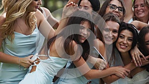 Pretty bridemaids in identical blue dresses run to hug bride together in park cheering waving hands. Woman party with