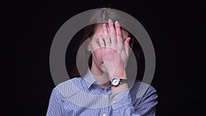 Pretty brunette businesswoman in blue blouse gestures facepalm being annoyed and irritated at black background.