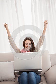 Pretty brunette cheering using laptop