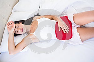 Pretty brunette with cramps on bed
