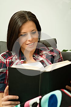 Pretty brunette girl reading on the sofa