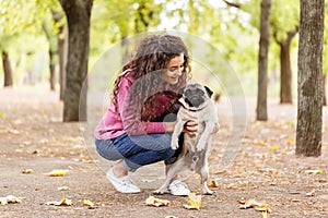 Pretty brunette girl walking with dog in the park. Animal concept.