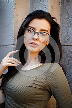 and pretty brunette in glasses posing on the streets.