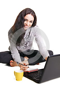 Pretty brunette with laptop writing at notebook