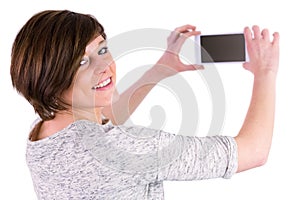 Pretty brunette looking at camera and taking a picture with her smartphone