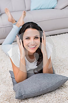 Pretty brunette lying on the rug listening to music