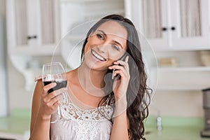 Pretty brunette on the phone having glass of wine