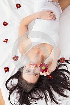 Pretty brunette posing in bed with flowers