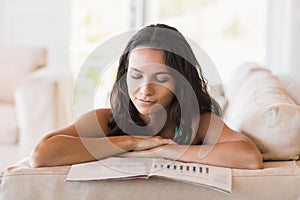 Pretty brunette reading magazine on the couch