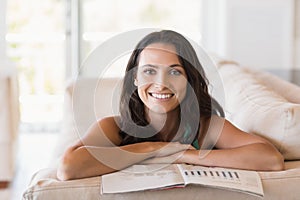 Pretty brunette reading magazine on the couch