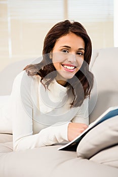 Pretty brunette reading magazine on the couch