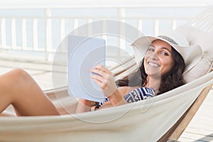 Pretty brunette relaxing on a hammock and using tablet pc