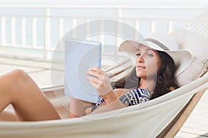 Pretty brunette relaxing on a hammock and using tablet pc