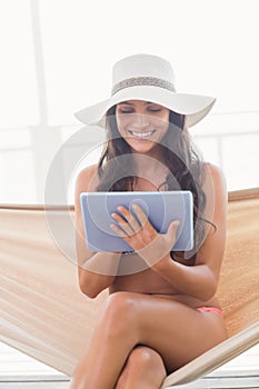 Pretty brunette relaxing on a hammock and using tablet pc