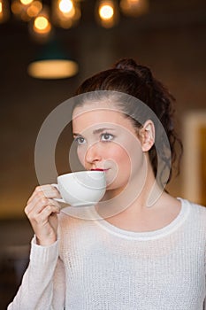 Pretty brunette sipping cup of coffee