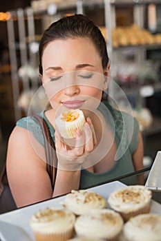 Pretty brunette smelling a cupcake