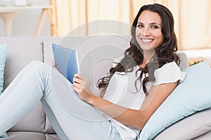 Pretty brunette using tablet pc on couch