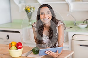 Pretty brunette using tablet pc and preparing salad