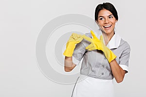 Pretty brunette woman in gray uniform taking off her yellow protective gloves while smiling and looking aside